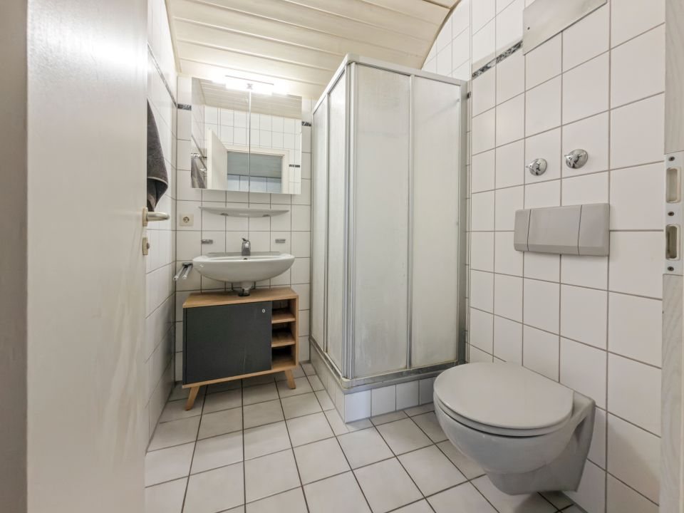 Badezimmer im Dachgeschoss mit Duschkabine, Waschbecken, Spiegelschrank und WC